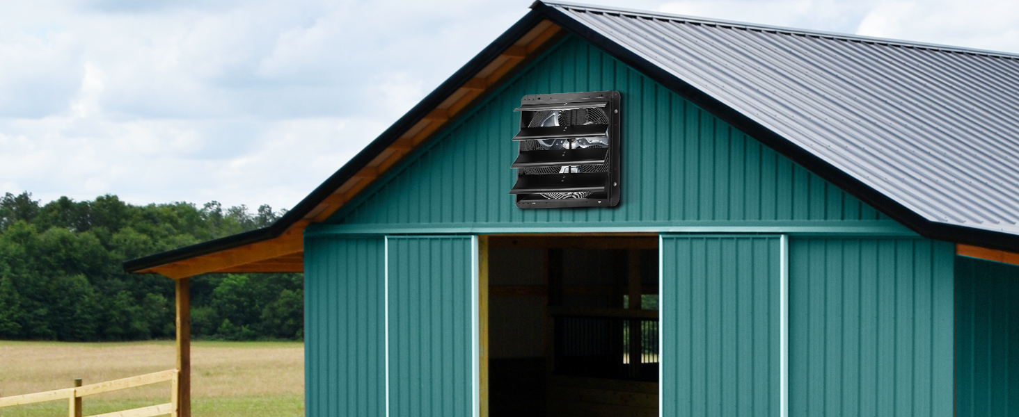 green barn with a black VEVOR shutter exhaust fan on the front wall under a cloudy sky.