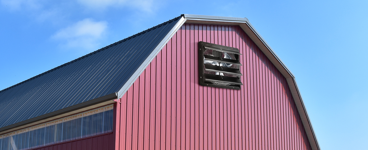 red barn with black VEVOR shutter exhaust fan on a blue sky background.